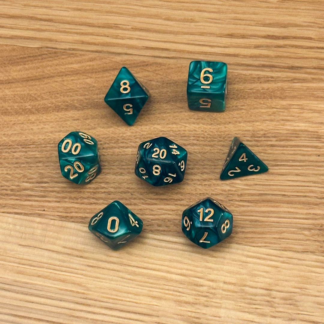Set of 7 polyhedral dice (D4, D6, D8, D10, percentile D10, D12, D20) in swirled emerald pearlescent acrylic with gold number infill.