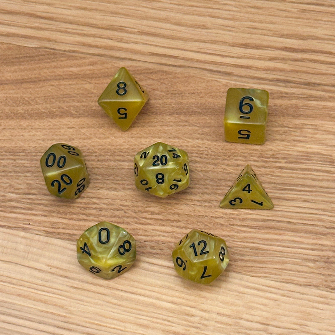 Set of 7 polyhedral dice (D4, D6, D8, D10, percentile D10, D12, D20) in swirled yellow acrylic with black number infill.