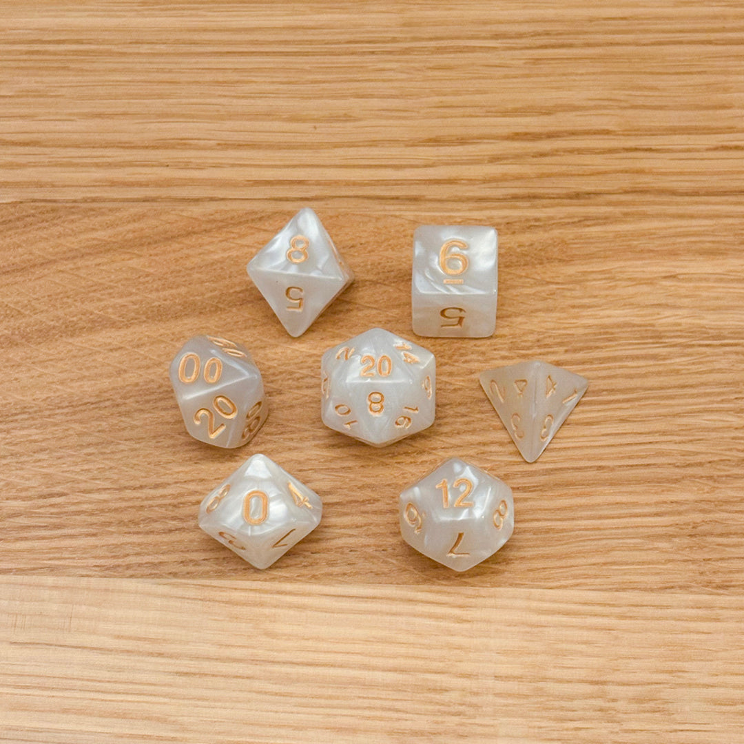 Set of 7 polyhedral dice (D4, D6, D8, D10, percentile D10, D12, D20) in swirled white pearlescent acrylic with gold number infill.