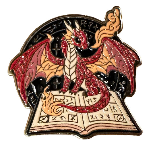 One-inch gold-tone soft enamel pin featuring a red glitter dragon sitting on a spell tome.