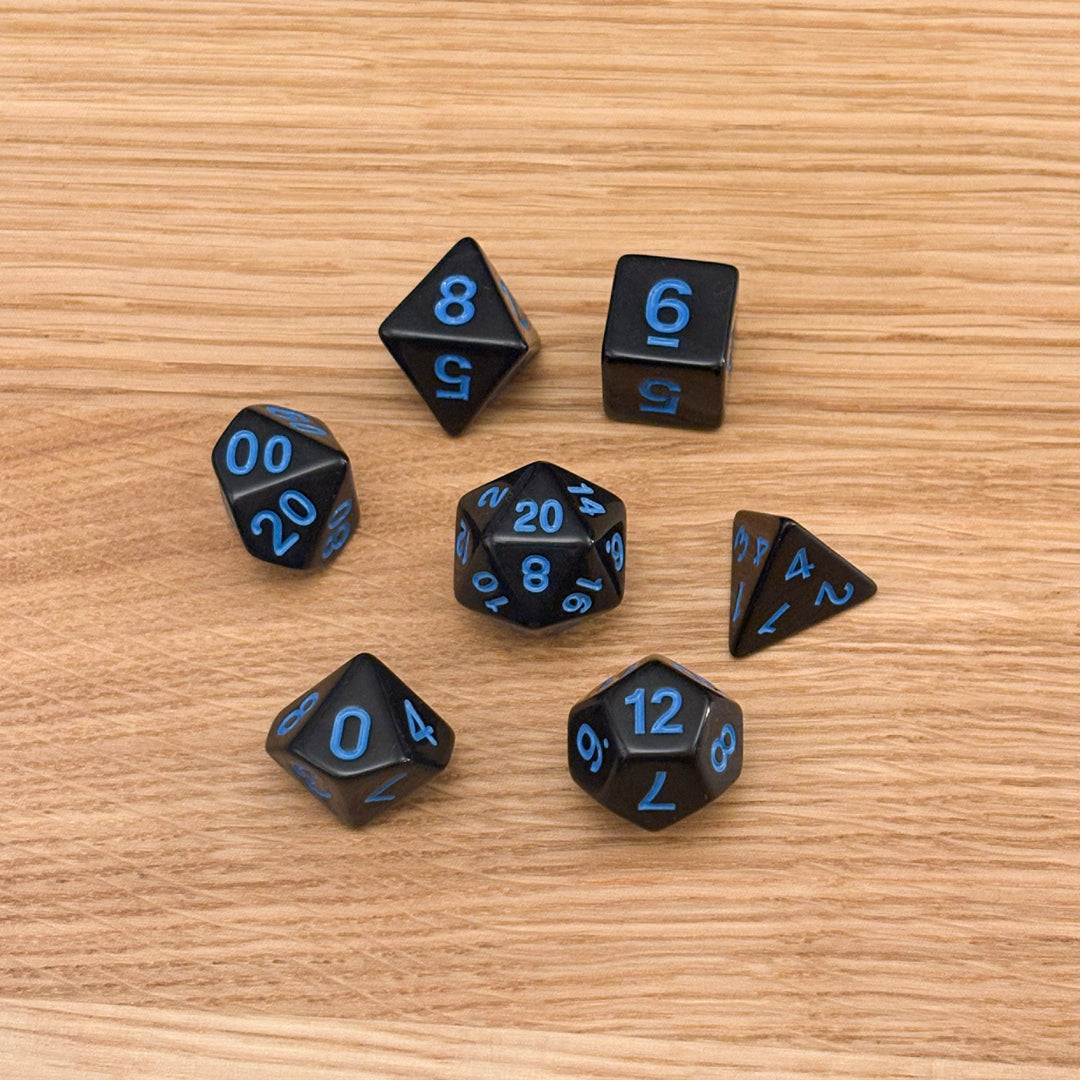 Set of 7 polyhedral dice (D4, D6, D8, D10, percentile D10, D12, D20) in solid black acrylic with blue number infill.