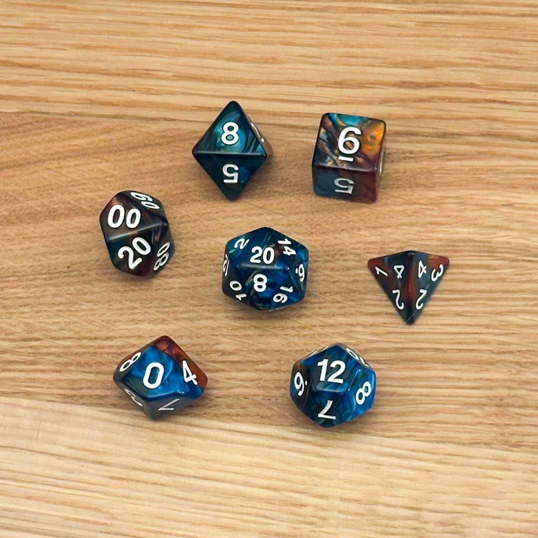 Set of 7 polyhedral dice (D4, D6, D8, D10, percentile D10, D12, D20) in swirled blue and copper acrylic with white number infill.