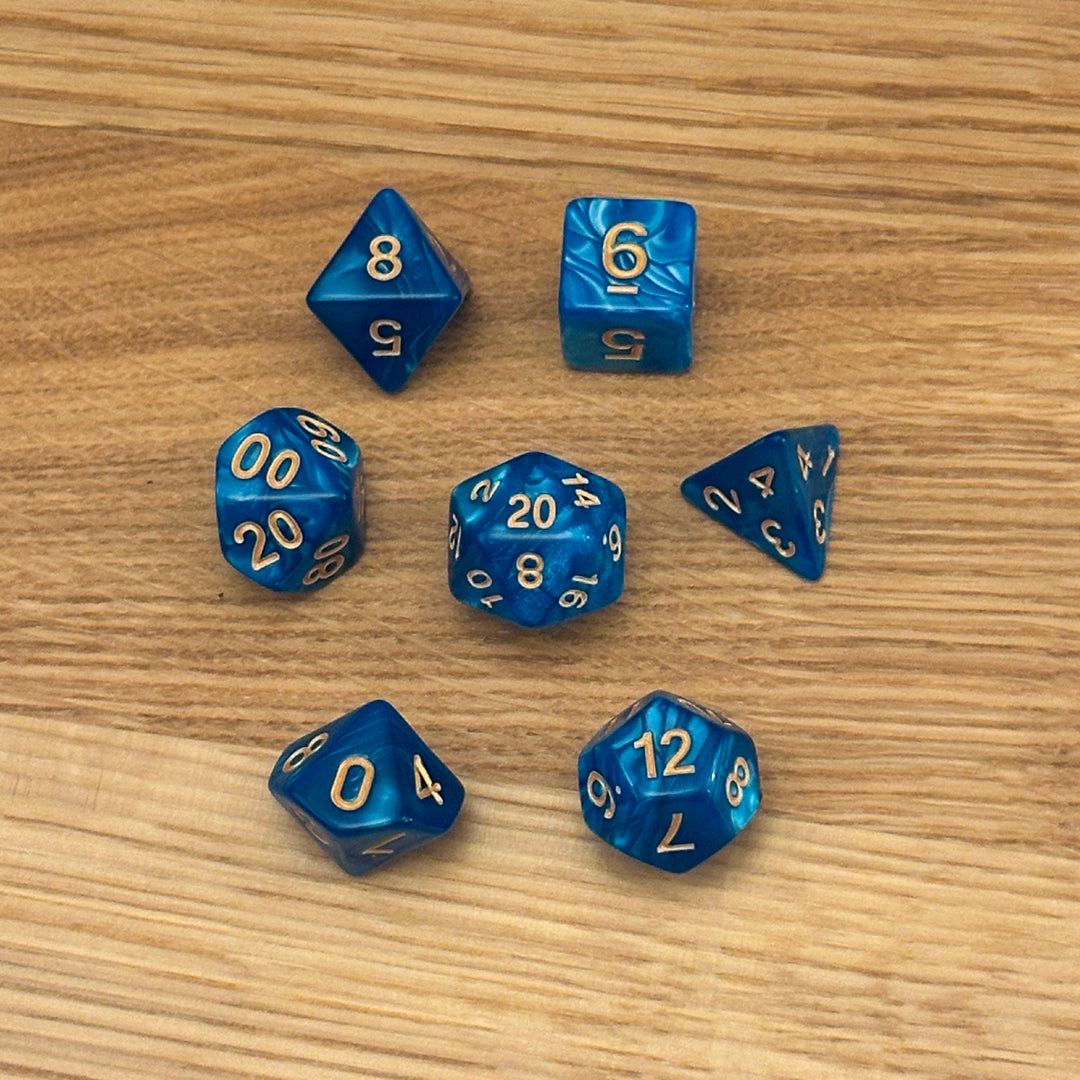 Set of 7 polyhedral dice (D4, D6, D8, D10, percentile D10, D12, D20) in swirled blue shimmer acrylic with gold number infill.