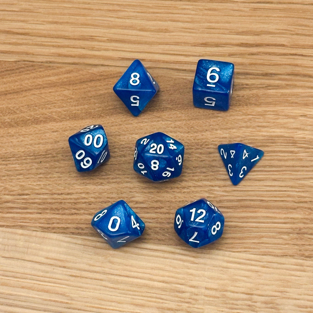 Set of 7 polyhedral dice (D4, D6, D8, D10, percentile D10, D12, D20) in swirled blue glitter acrylic with white number infill.