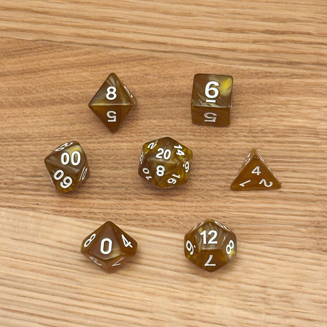 Set of 7 polyhedral dice (D4, D6, D8, D10, percentile D10, D12, D20) in swirled mustard yellow acrylic with white number infill.