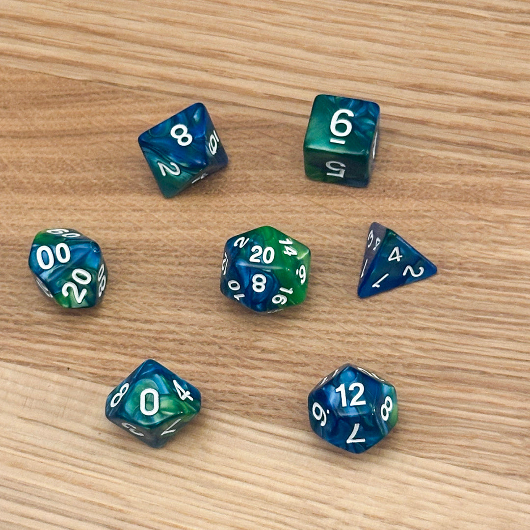 Set of 7 polyhedral dice (D4, D6, D8, D10, percentile D10, D12, D20) in swirled green and blue acrylic with white number infill.