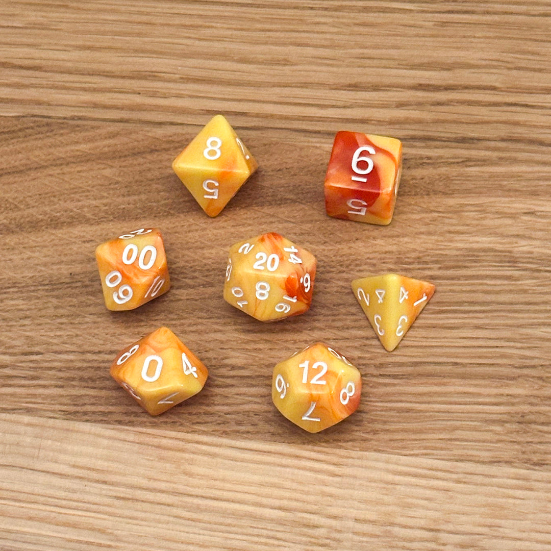 Set of 7 polyhedral dice (D4, D6, D8, D10, percentile D10, D12, D20) in swirled yellow and orange acrylic with white number infill.