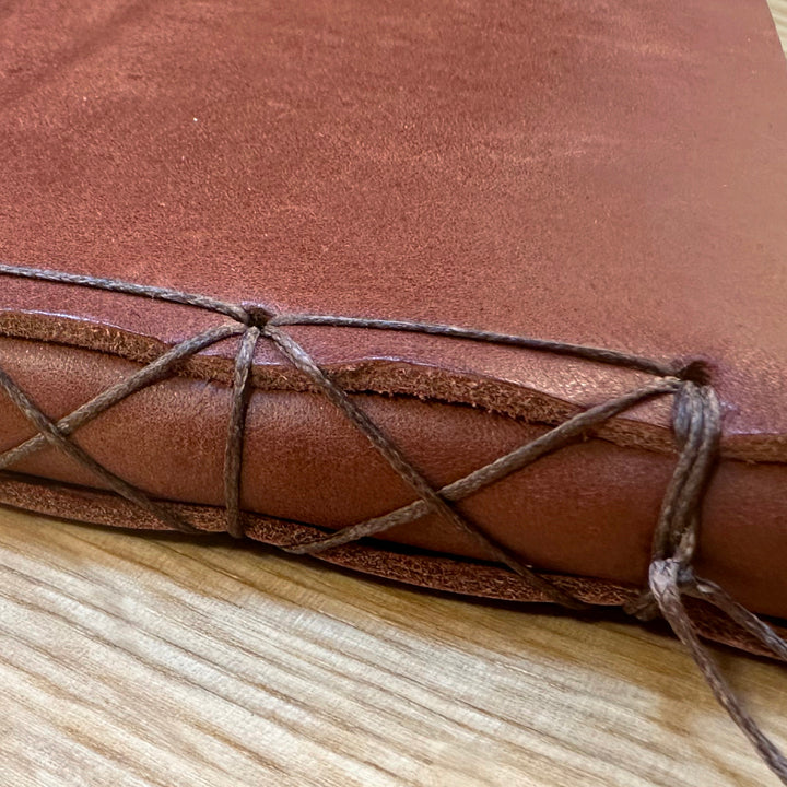 Close-up of the hand-stitched spine of a vegetable-tanned leather journal.
